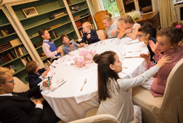 De kinderen zitten allemaal aan de tafel bij de communicant en zijn gezellig met elkaar aan het babbelen