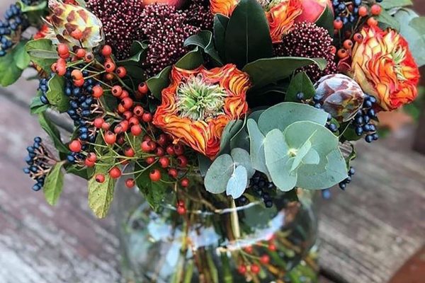 Rozen, bessen, appeltjes en eucalyptus, verwerkt in een herfstboeket