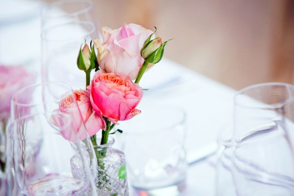 De tafel wordt versierd met een vaasje gevuld met enkele roosjes voor een communiefeest