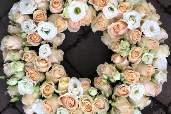 Licht roze en witte rozen in een rouwkrans Frm