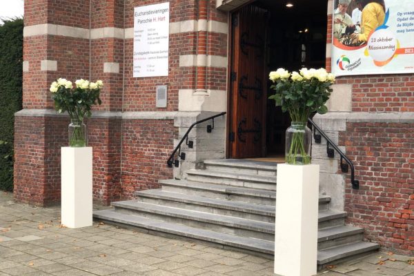 Grote boeketten op sokkel aan de ingang van de kerk FRM